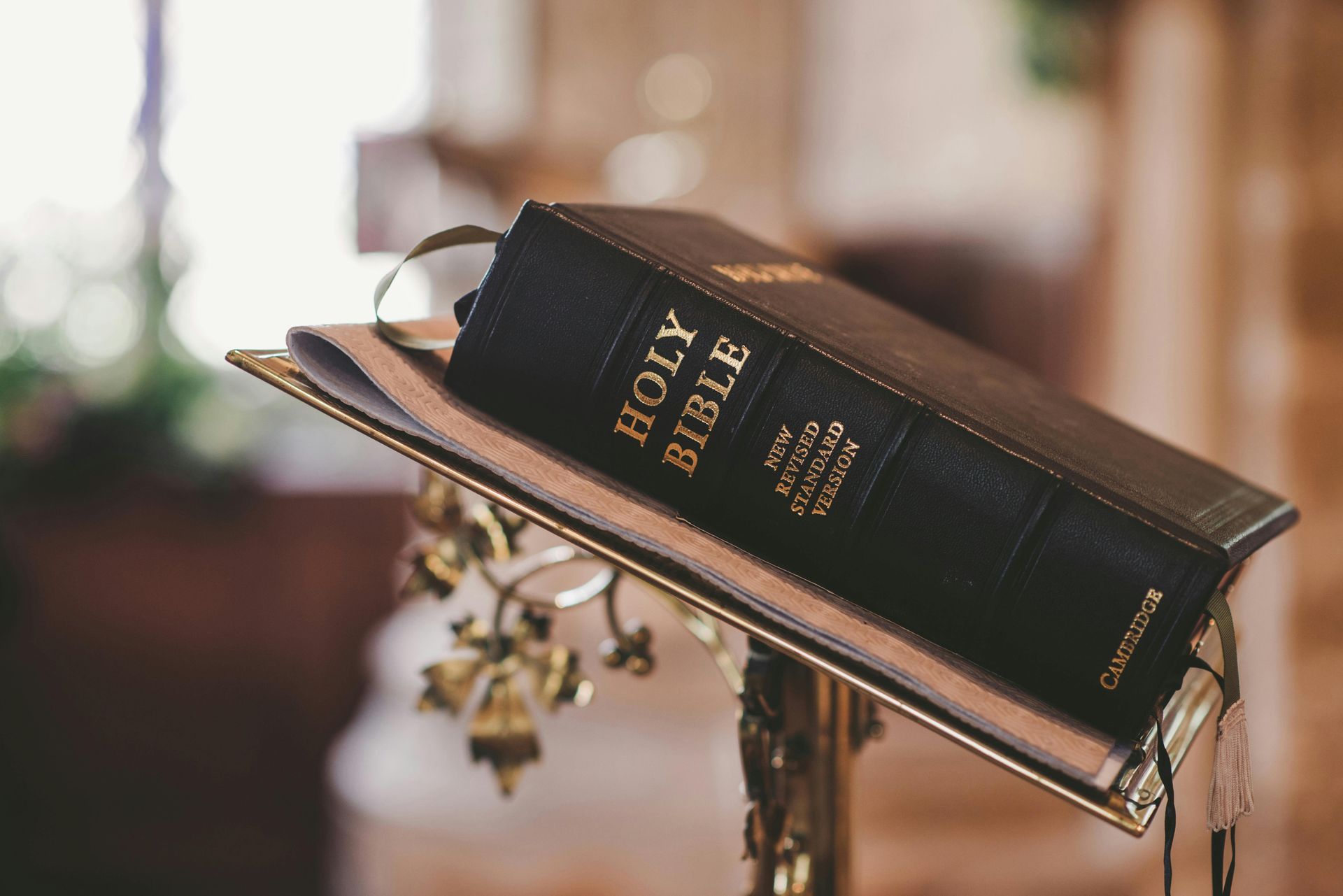 Black Holy Bible on a brass book stand inside, with a blurred background.