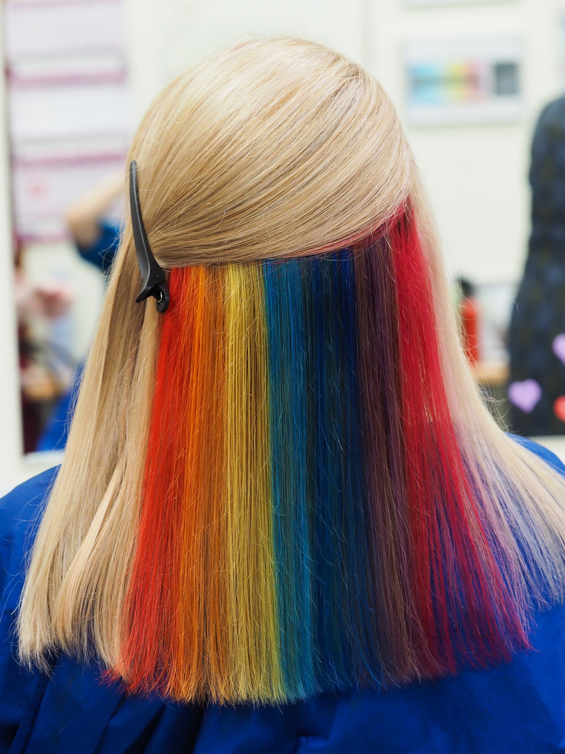 Blonde hair with a rainbow-colored strip of hair underneath, arranged in vertical stripes.