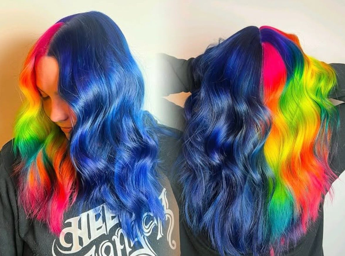 A woman with rainbow hair is wearing a black shirt.