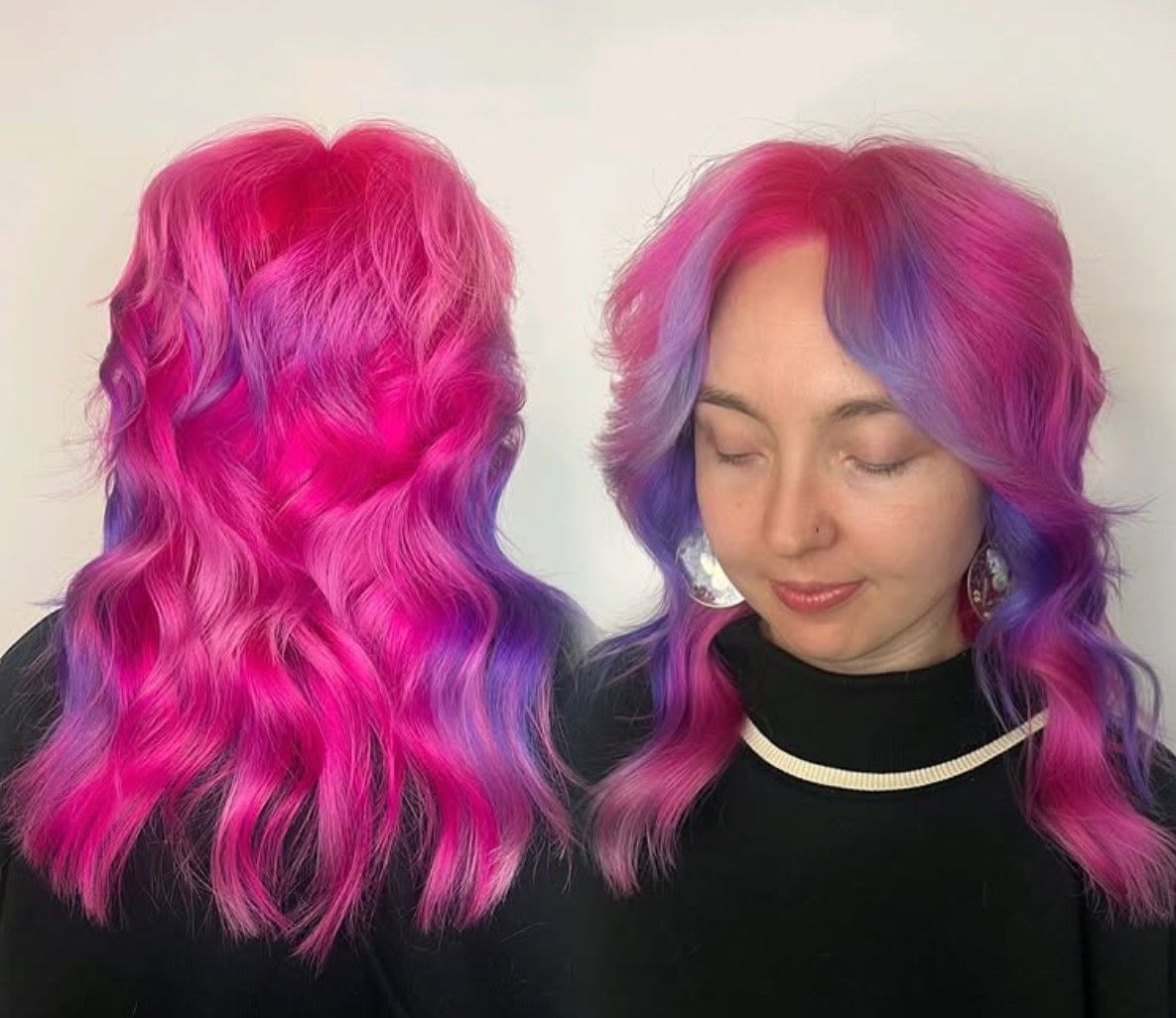 A woman with pink and purple hair is wearing a black turtleneck.