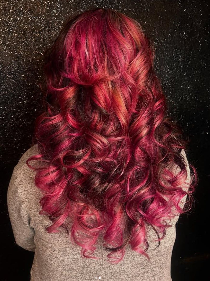 A woman with long red hair is wearing a grey sweater.