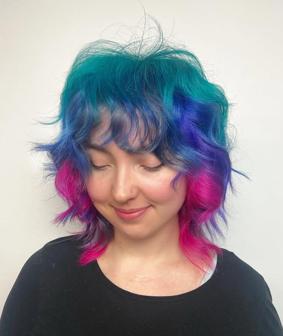 A woman with blue and pink hair is wearing a black shirt.