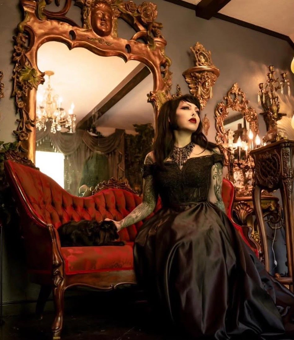 A woman in a black dress is sitting on a red couch