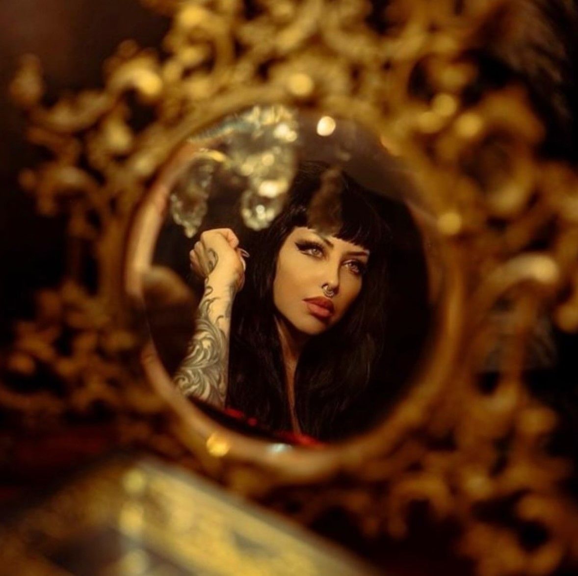 A woman with a tattoo on her arm is looking at herself in a mirror