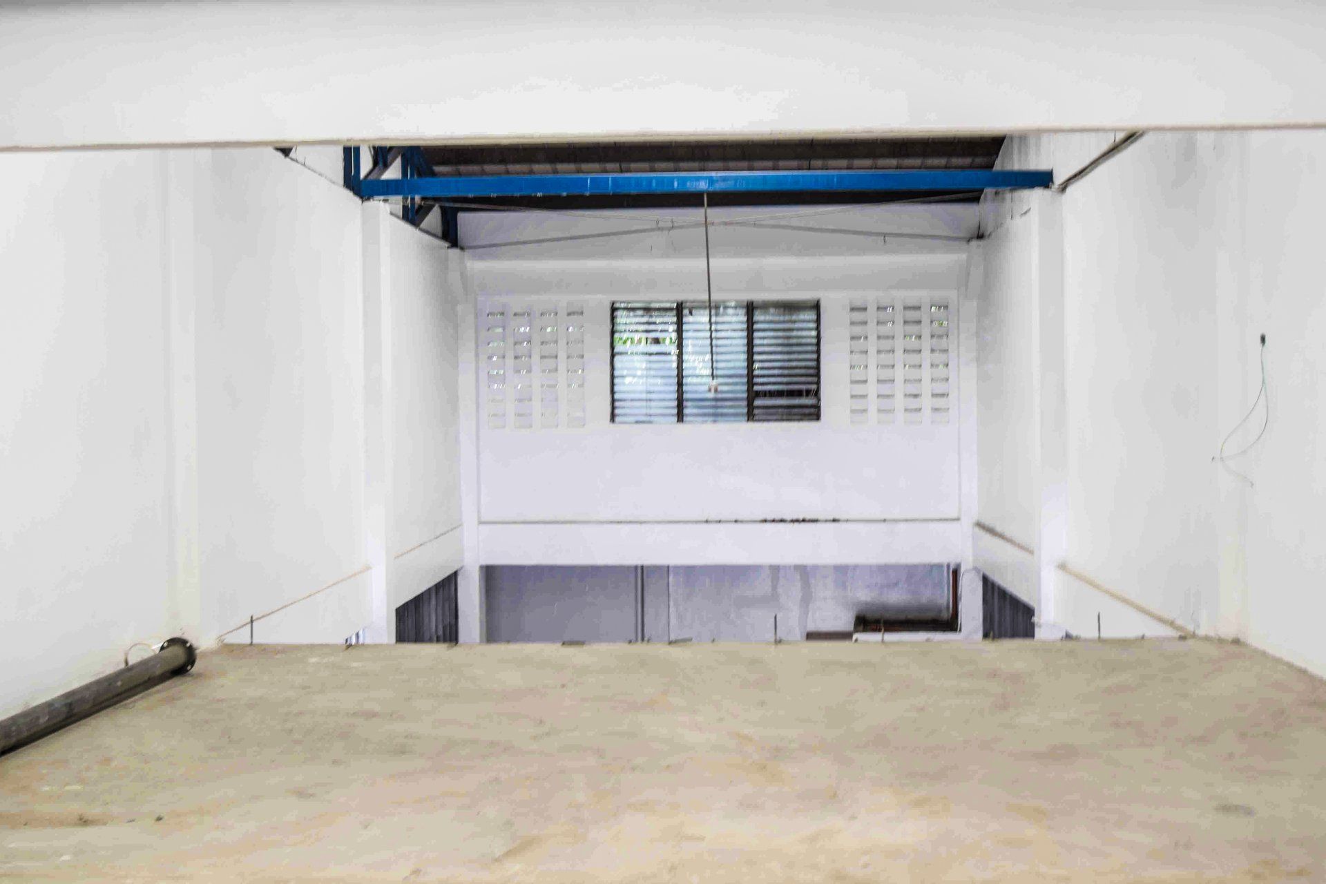 A white building with a wooden floor and a blue pipe hanging from the ceiling.