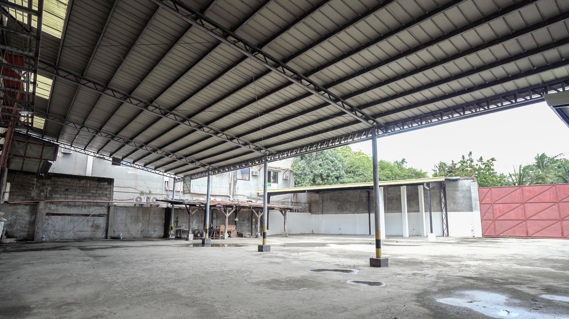 An empty warehouse with a metal roof and a red door