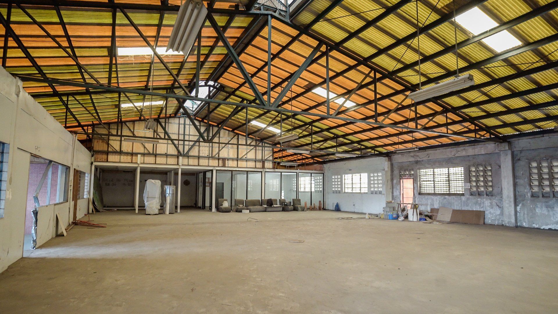 An empty warehouse with a yellow roof and a lot of windows.