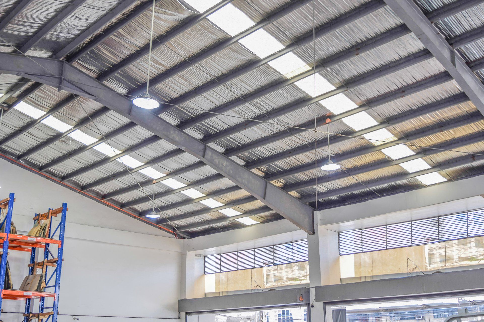 The ceiling of a large warehouse with lots of shelves and lights.