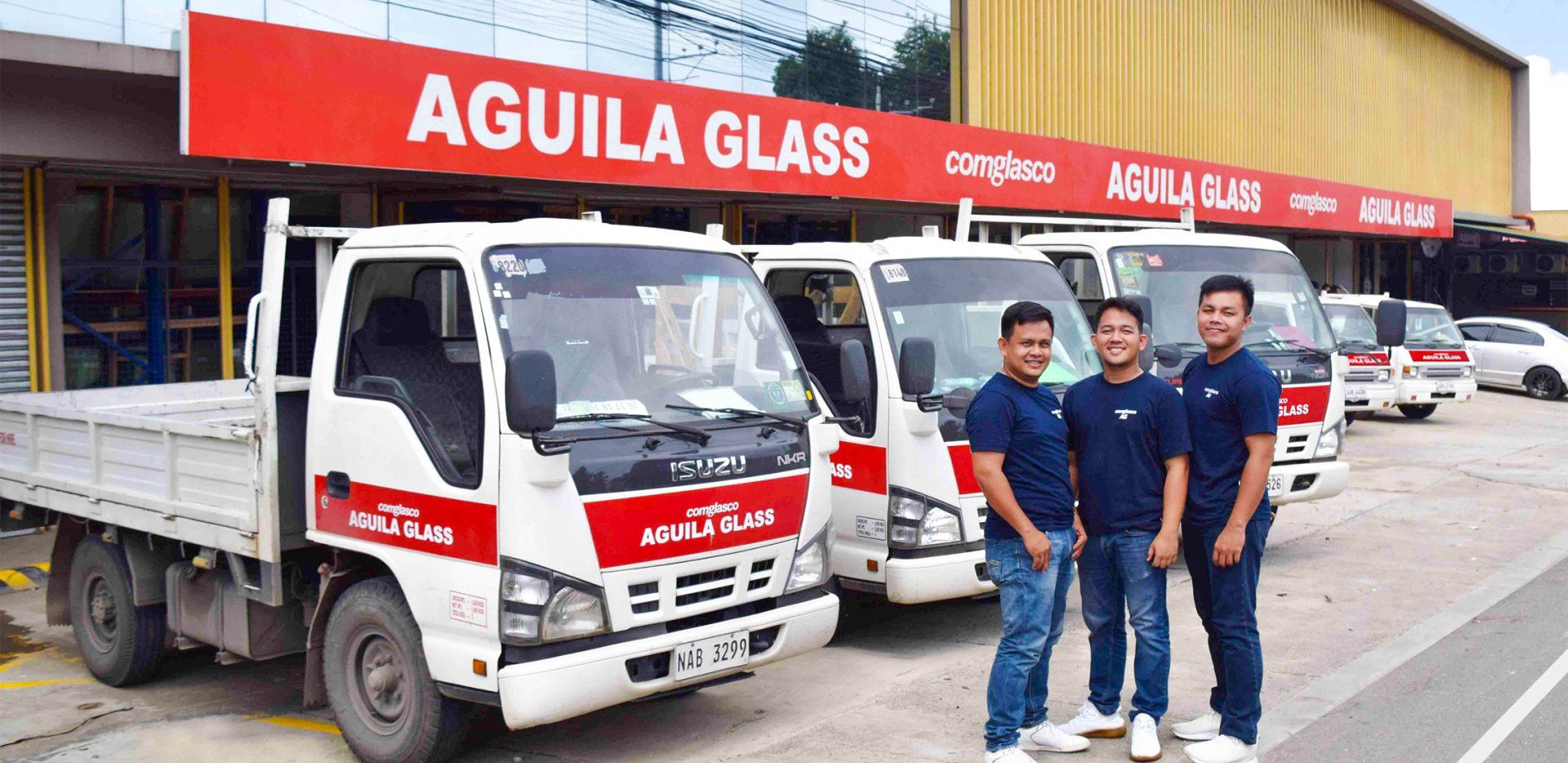 A group of men are standing in front of a row of trucks parked in front of a building.