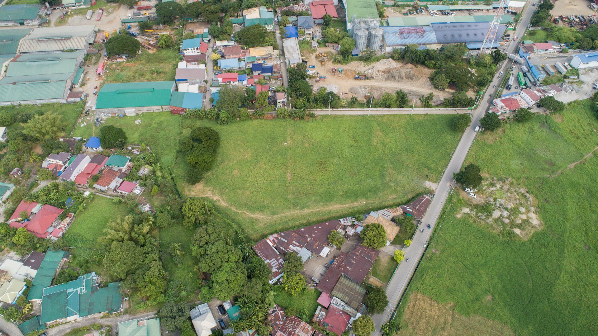 An aerial view of a residential area with a large grassy field in the middle.