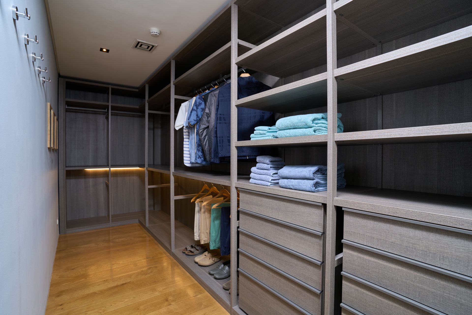 A walk in closet with lots of shelves and drawers