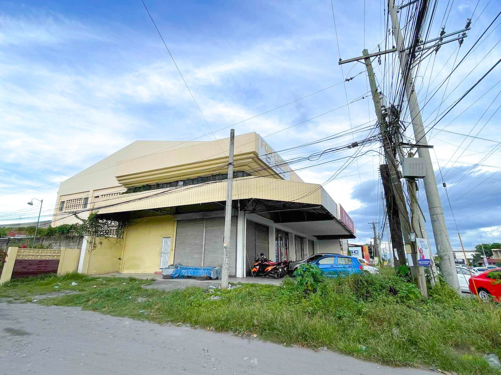 A large building is sitting on the side of a road next to a telephone pole.