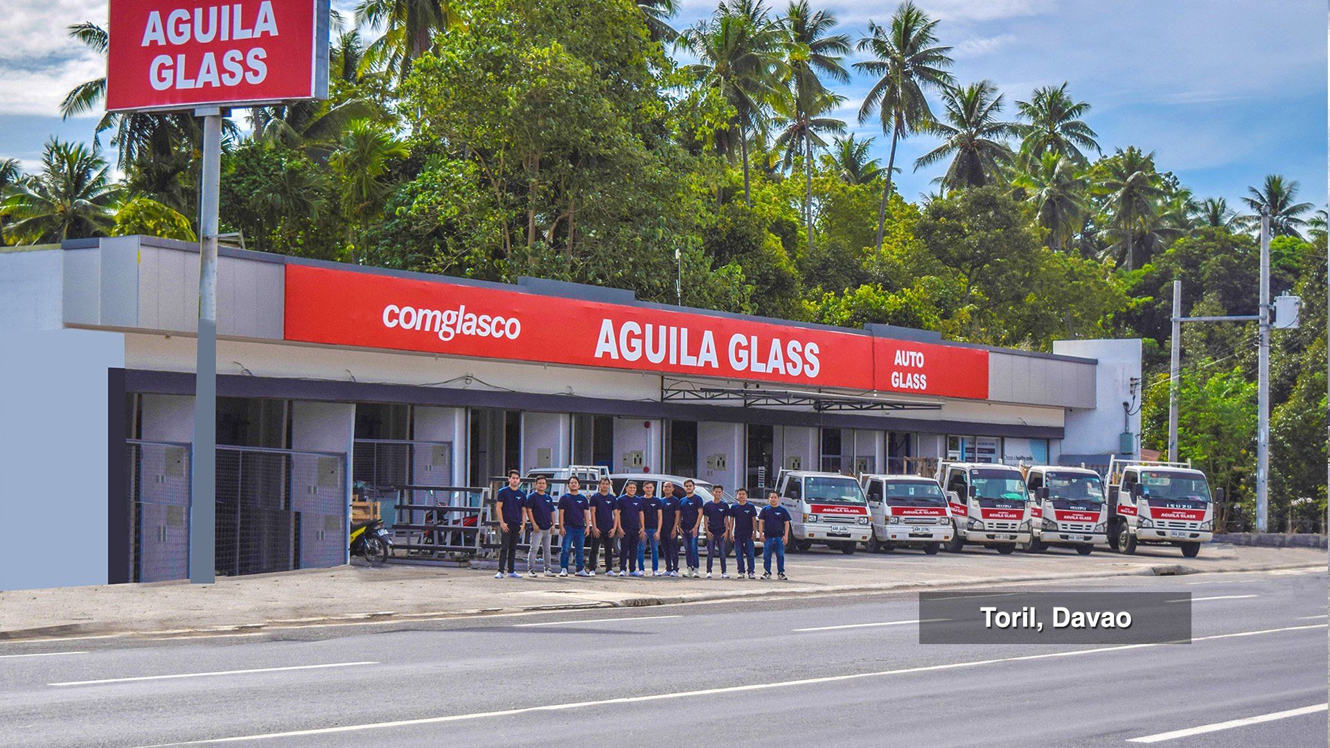 A group of people standing in front of a building that says aguila glass