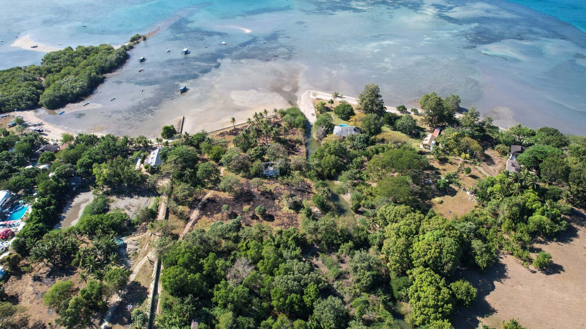 An aerial view of a small island in the middle of the ocean surrounded by trees.