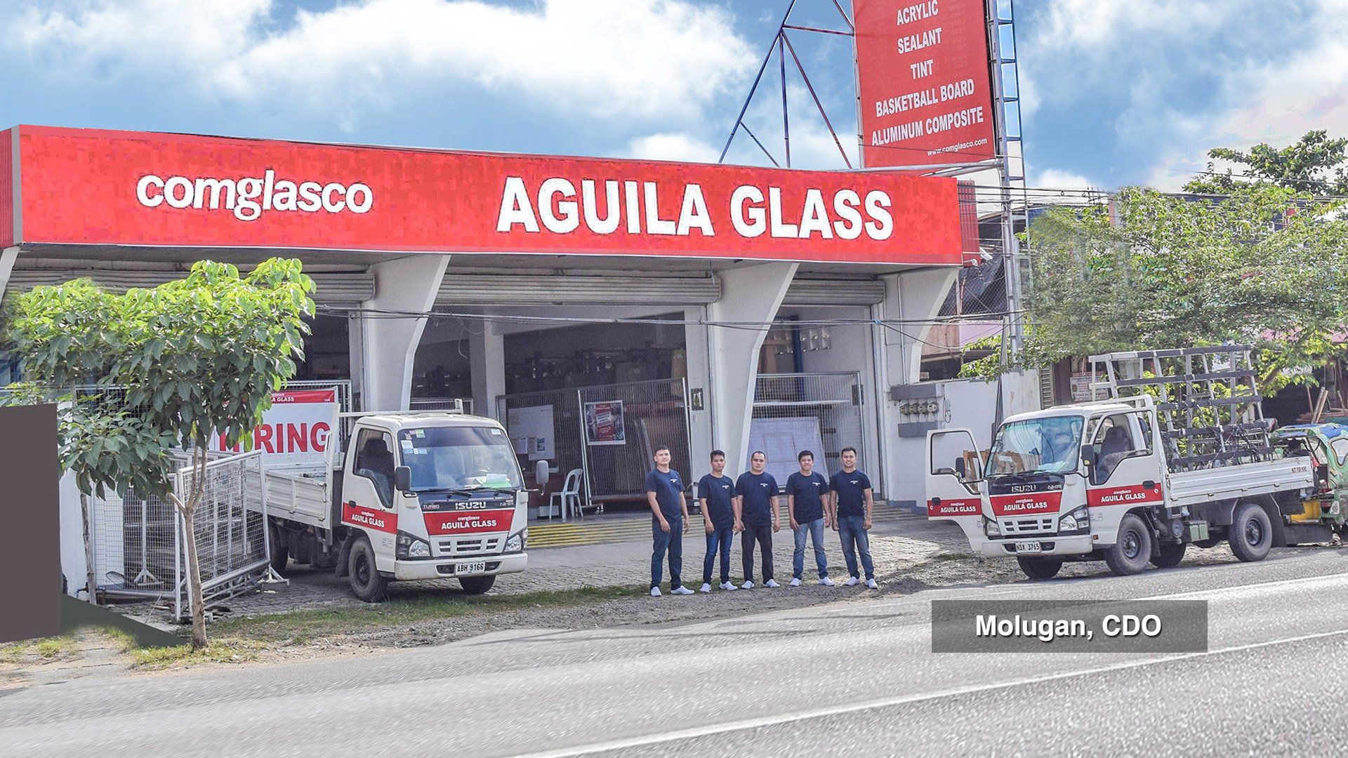 A group of people standing in front of a building that says aguila glass.