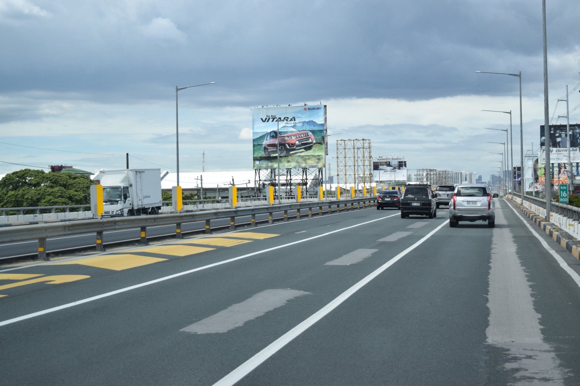 Cars are driving down a highway with a large billboard in the background
