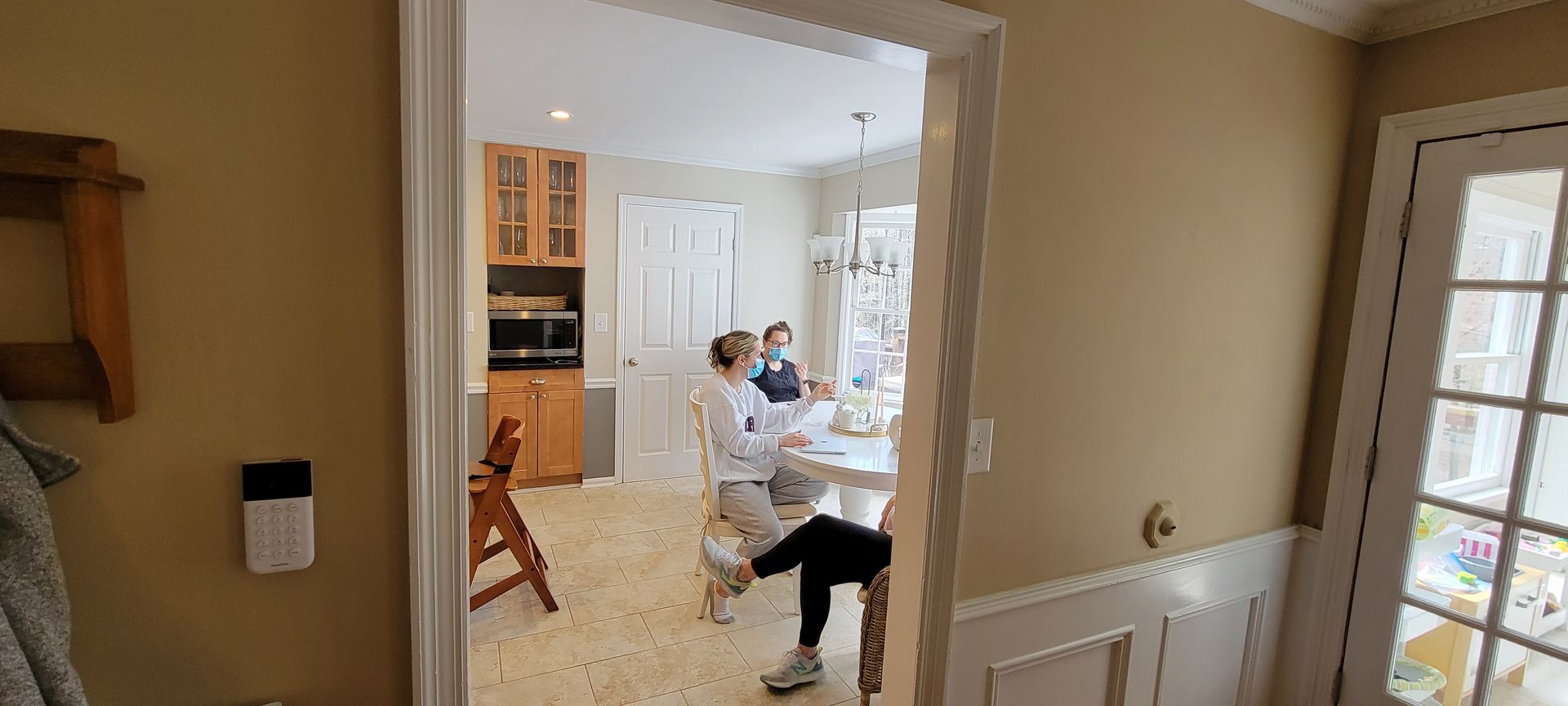A person sitting at a white table with two other people. They are in a dining room.