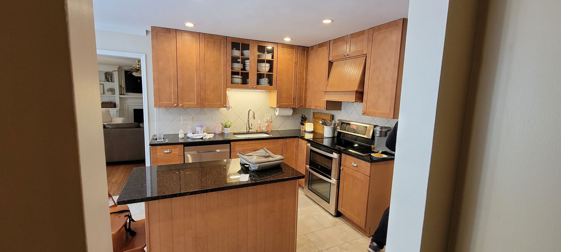 Kitchen with light wood cabinets, dark granite countertops, and stainless steel appliances.
