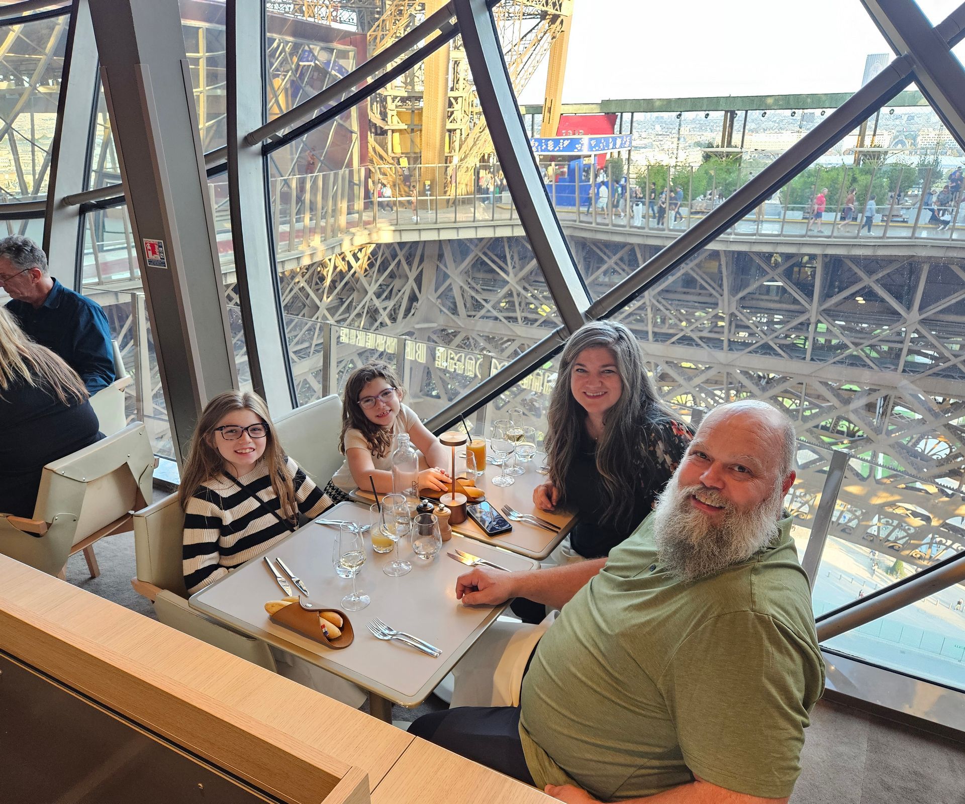 Family dining at a table inside the Eiffel Tower restaurant, with a view of the tower and the city.