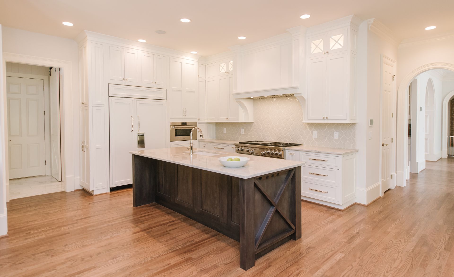 Spacious white kitchen with dark wood island, stainless steel appliances, and hardwood floors.