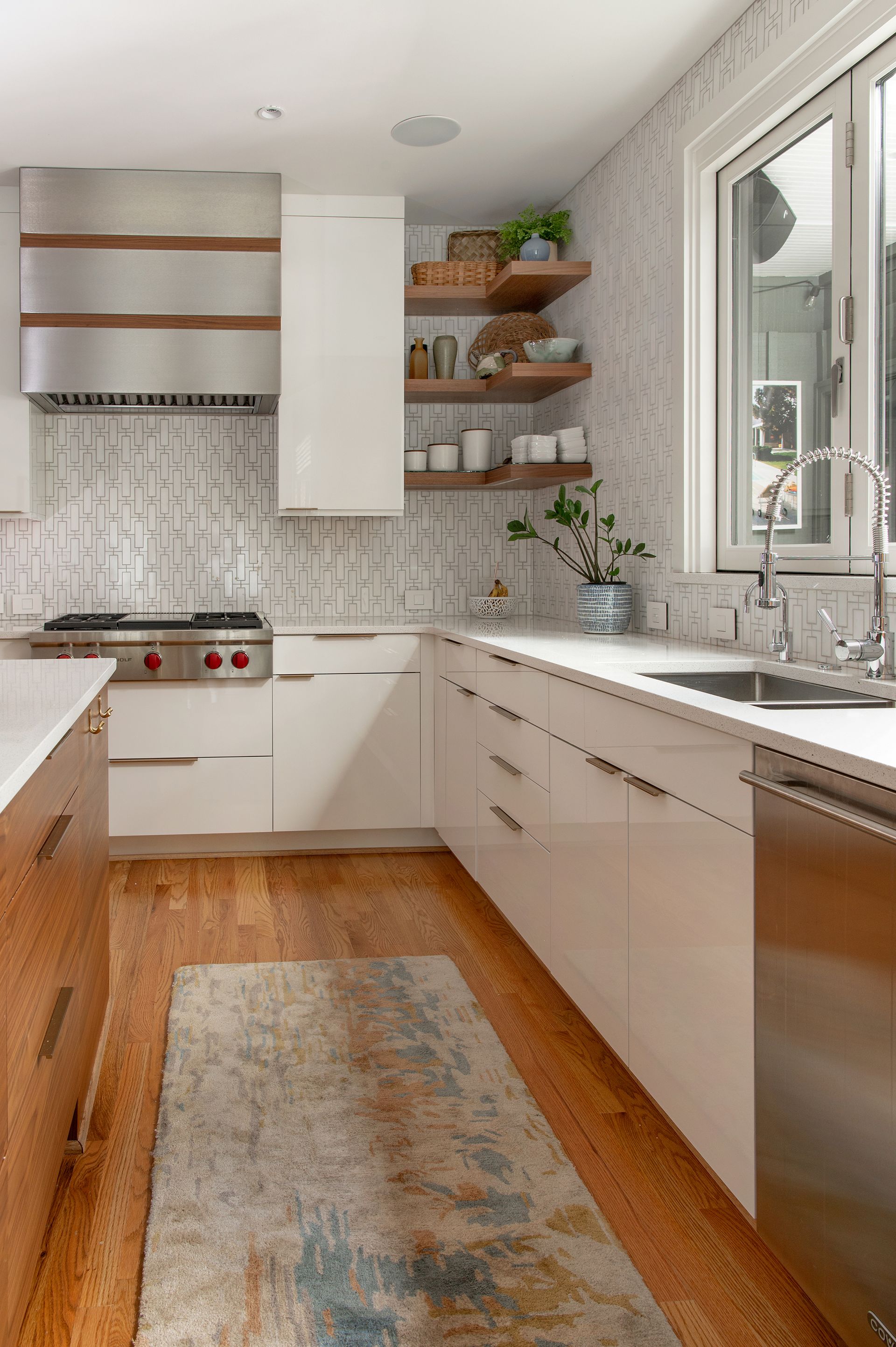 Modern kitchen with white cabinets, wood accents, and a patterned backsplash.
