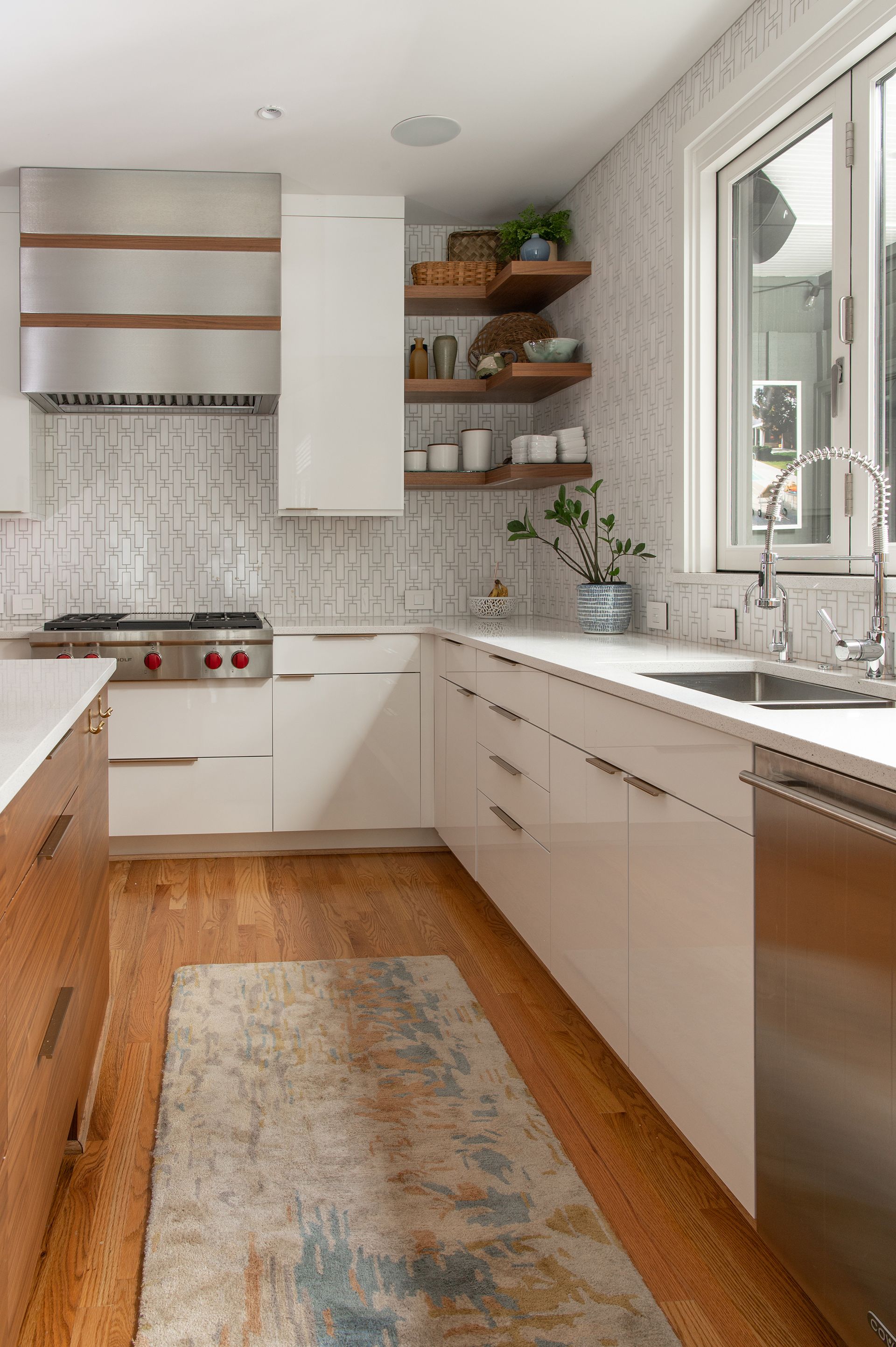Modern kitchen with white cabinets, wood accents, and patterned backsplash.