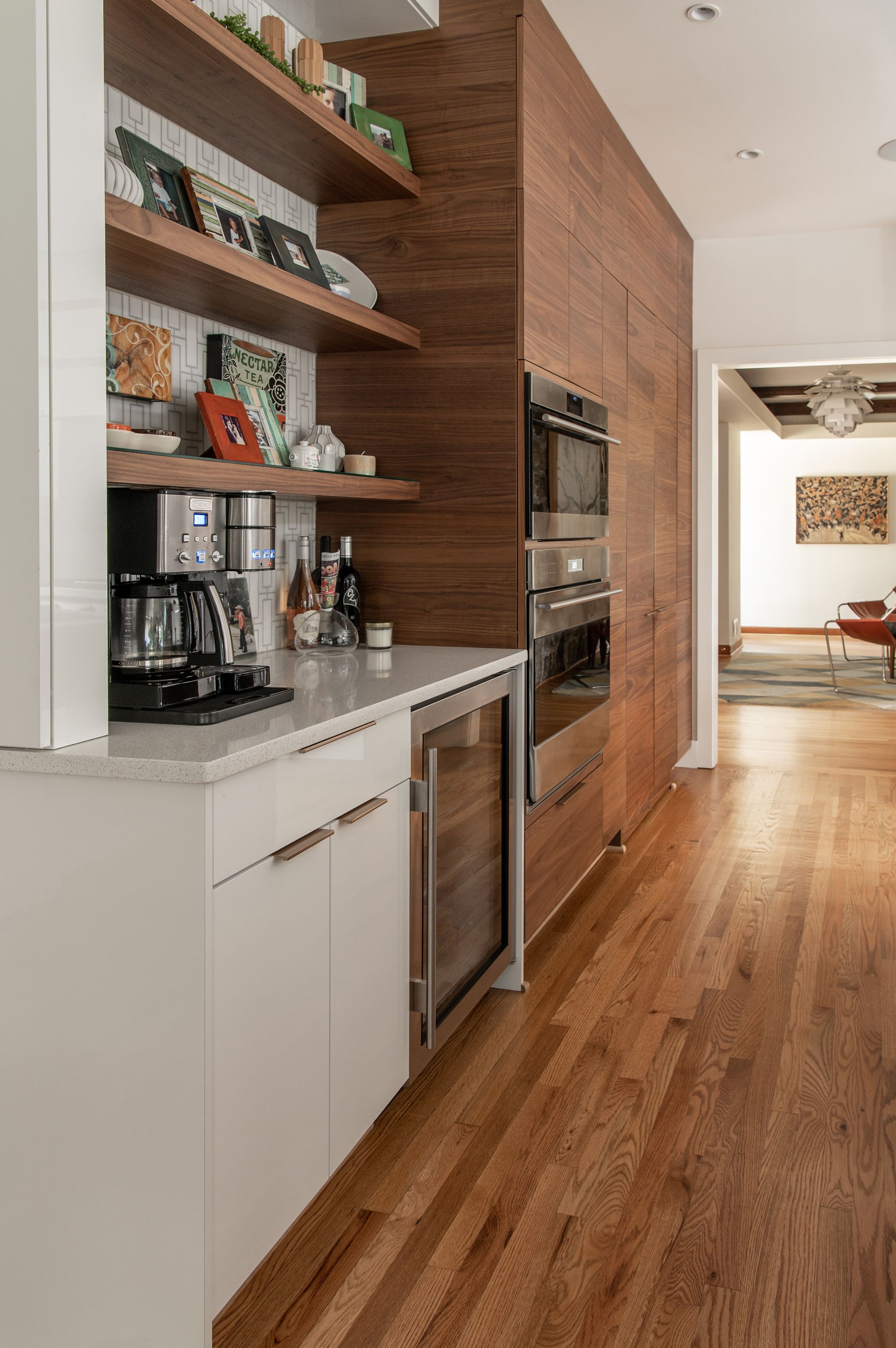 Modern kitchen with wood shelving, white cabinets, and built-in appliances.