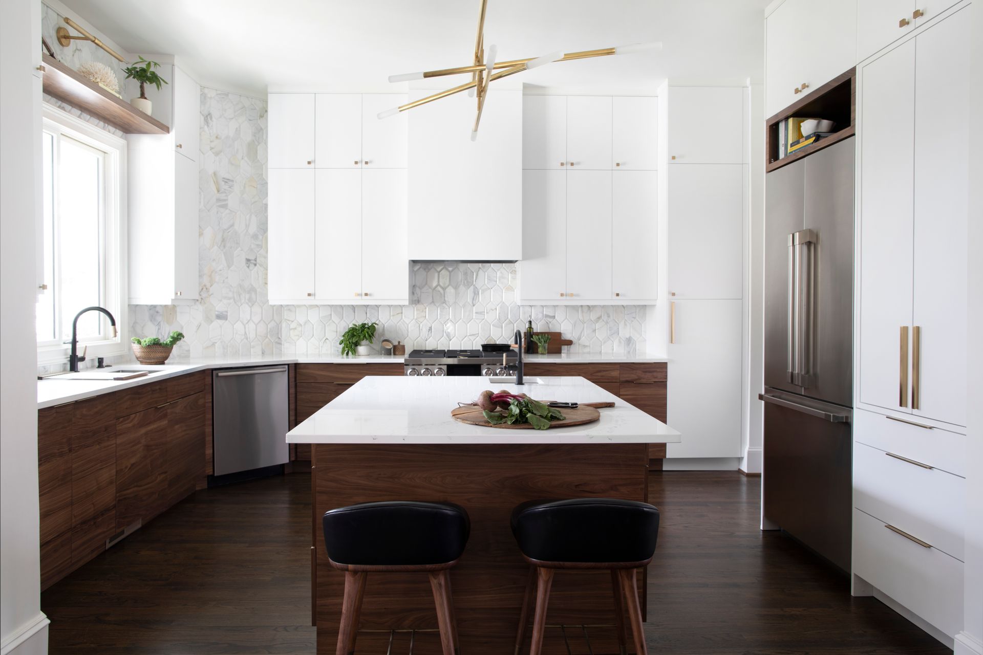 Modern kitchen with white upper cabinets, wood lower cabinets, island, and dark wood floor.
