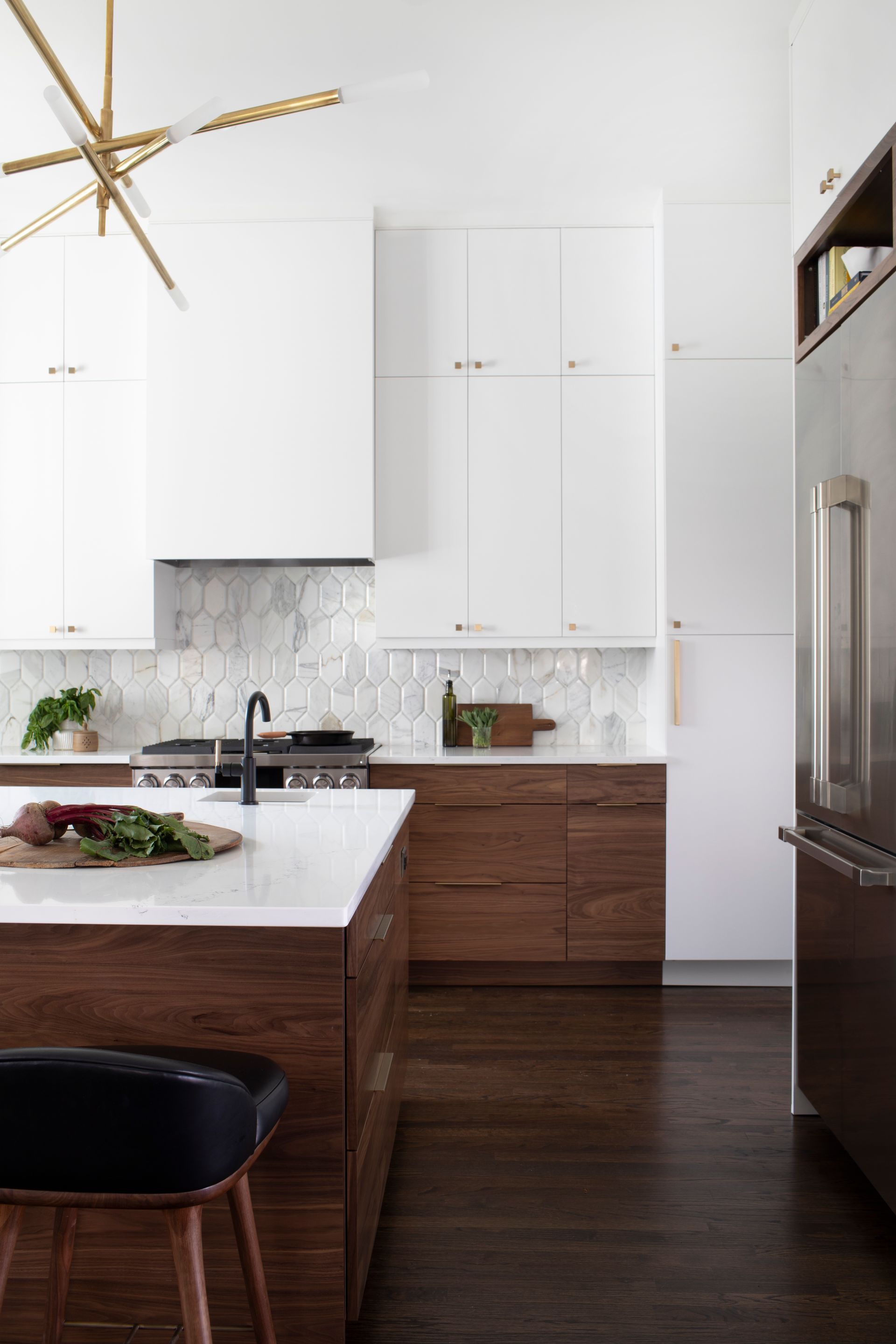 Modern kitchen with white upper cabinets, wood lower cabinets, and marble backsplash.