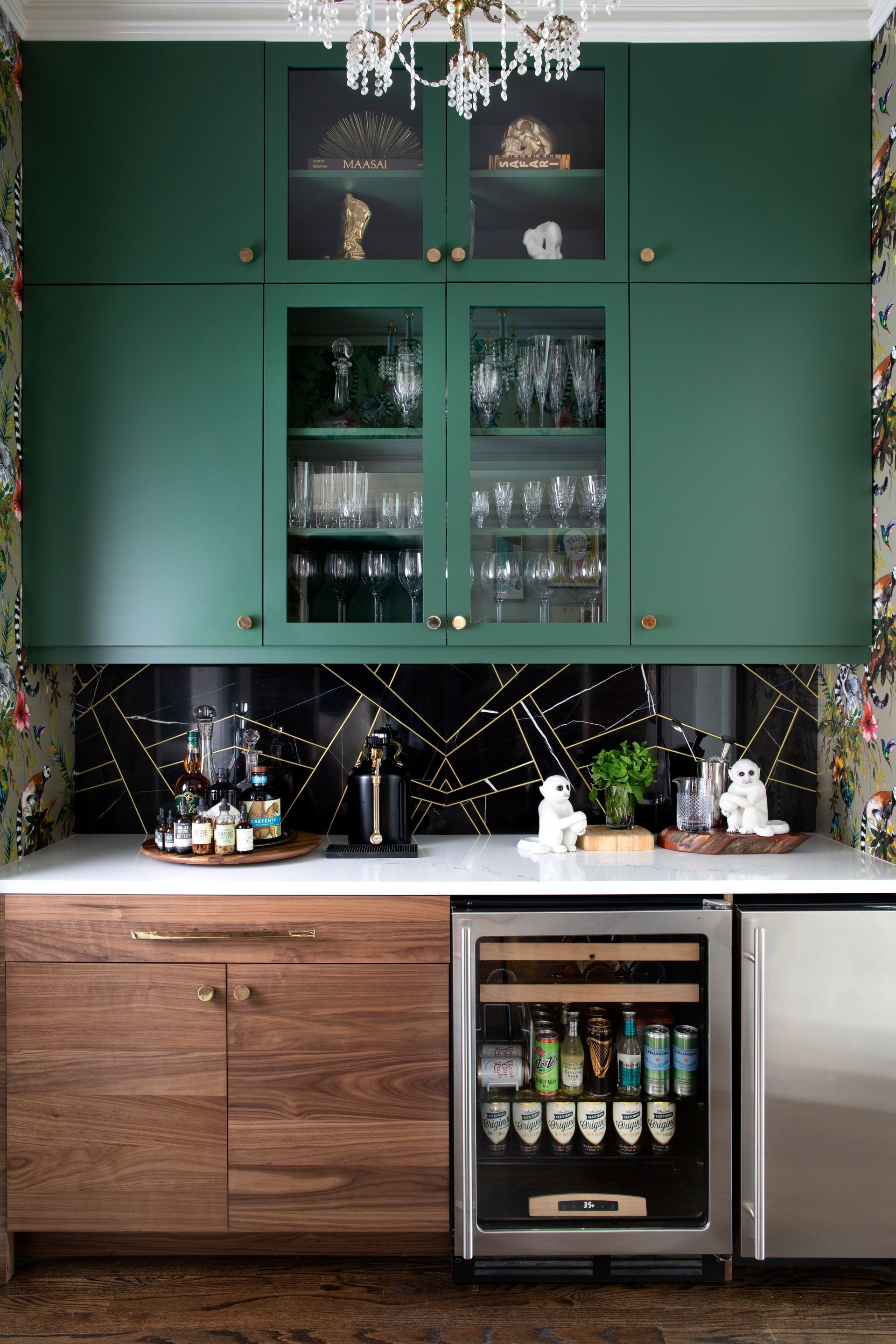 Green and wood-tone home bar with glass-front cabinets. White countertop, wine fridge, and decorative backsplash.