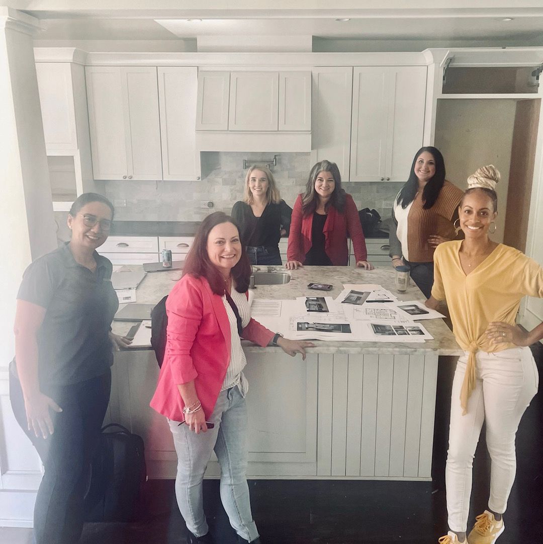 Group of people gathered around a kitchen island with displays.