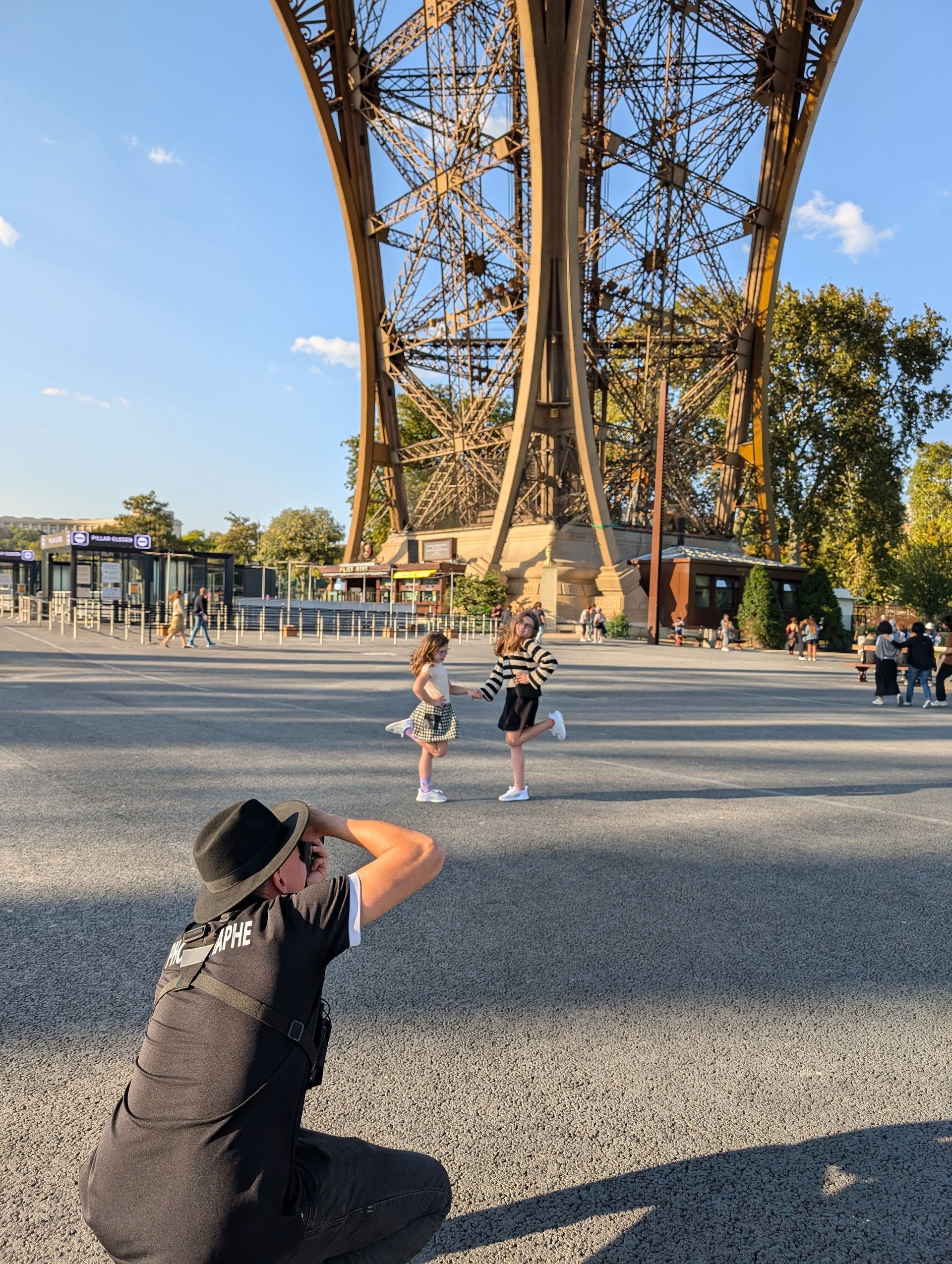 Photographer kneels to take pictures of two children near the Eiffel Tower, Paris.