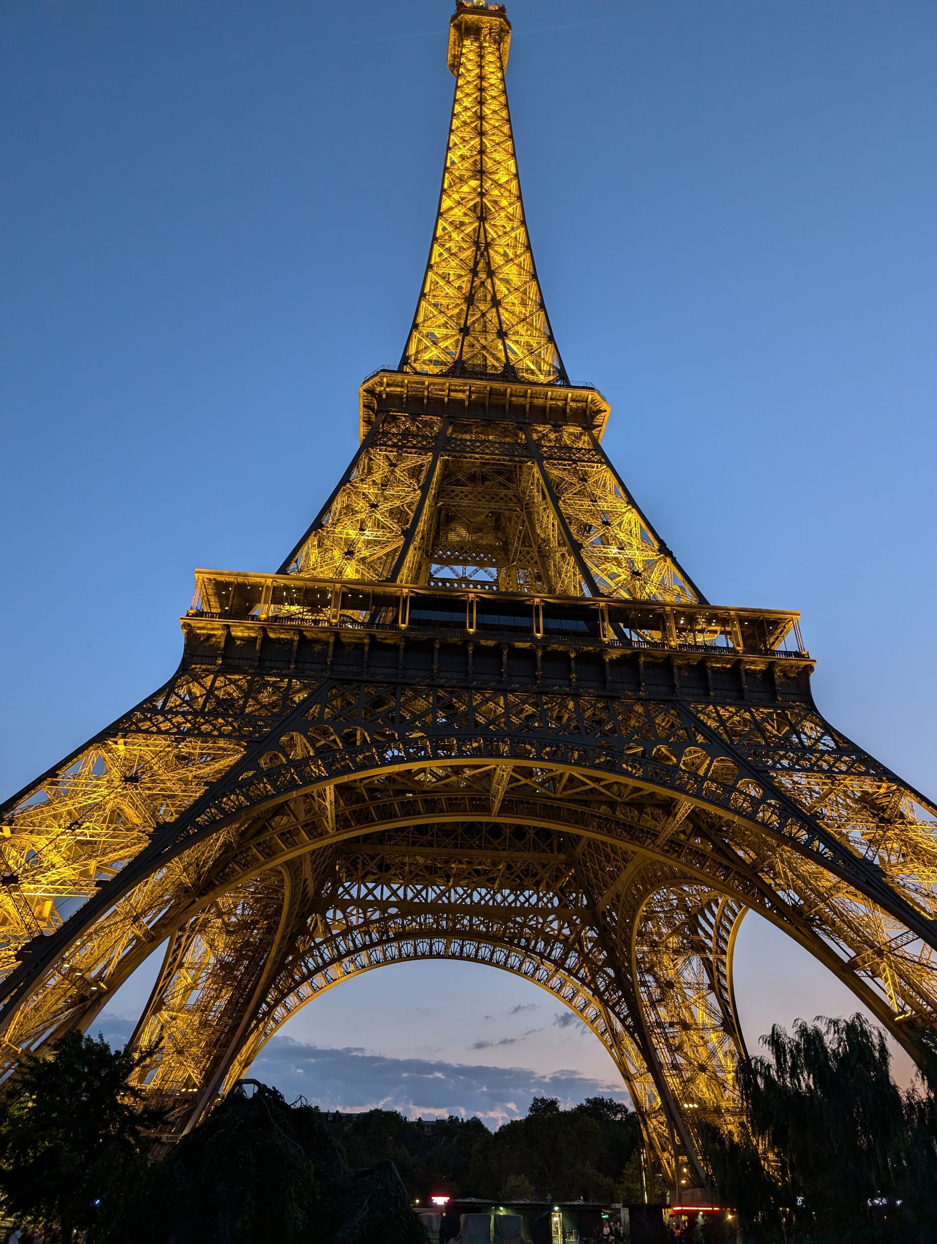 Eiffel Tower illuminated at dusk against a blue sky.