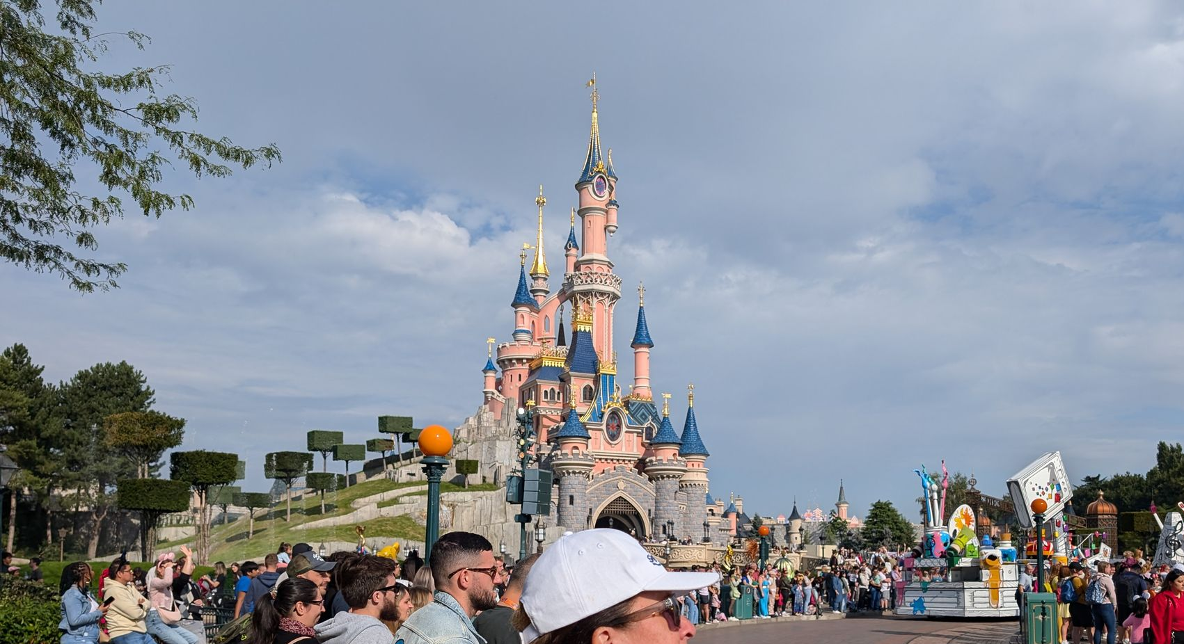 Sleeping Beauty Castle at Disneyland Paris with a parade in progress. People are watching.