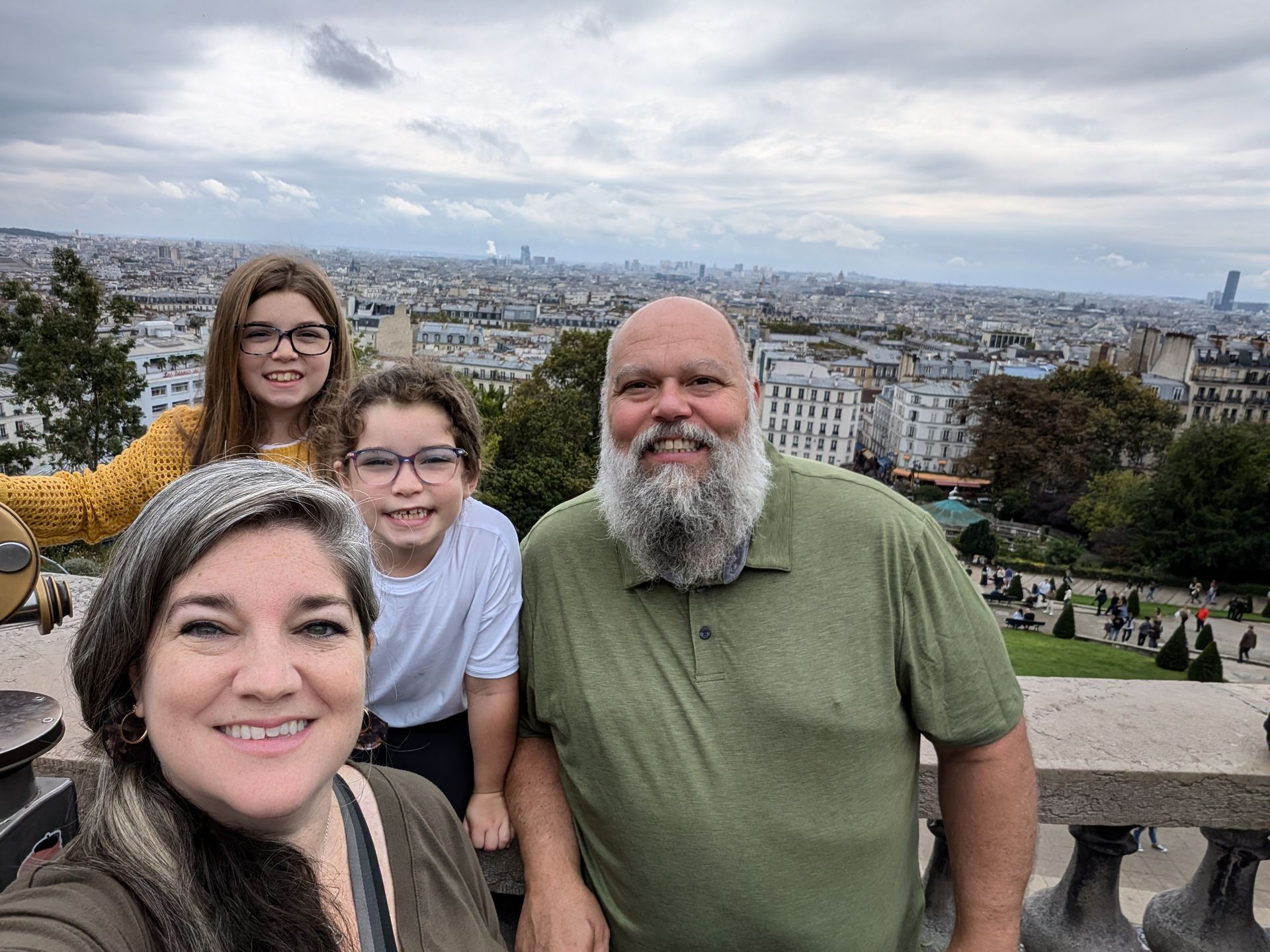 Family posing for a photo overlooking a city, overcast day.