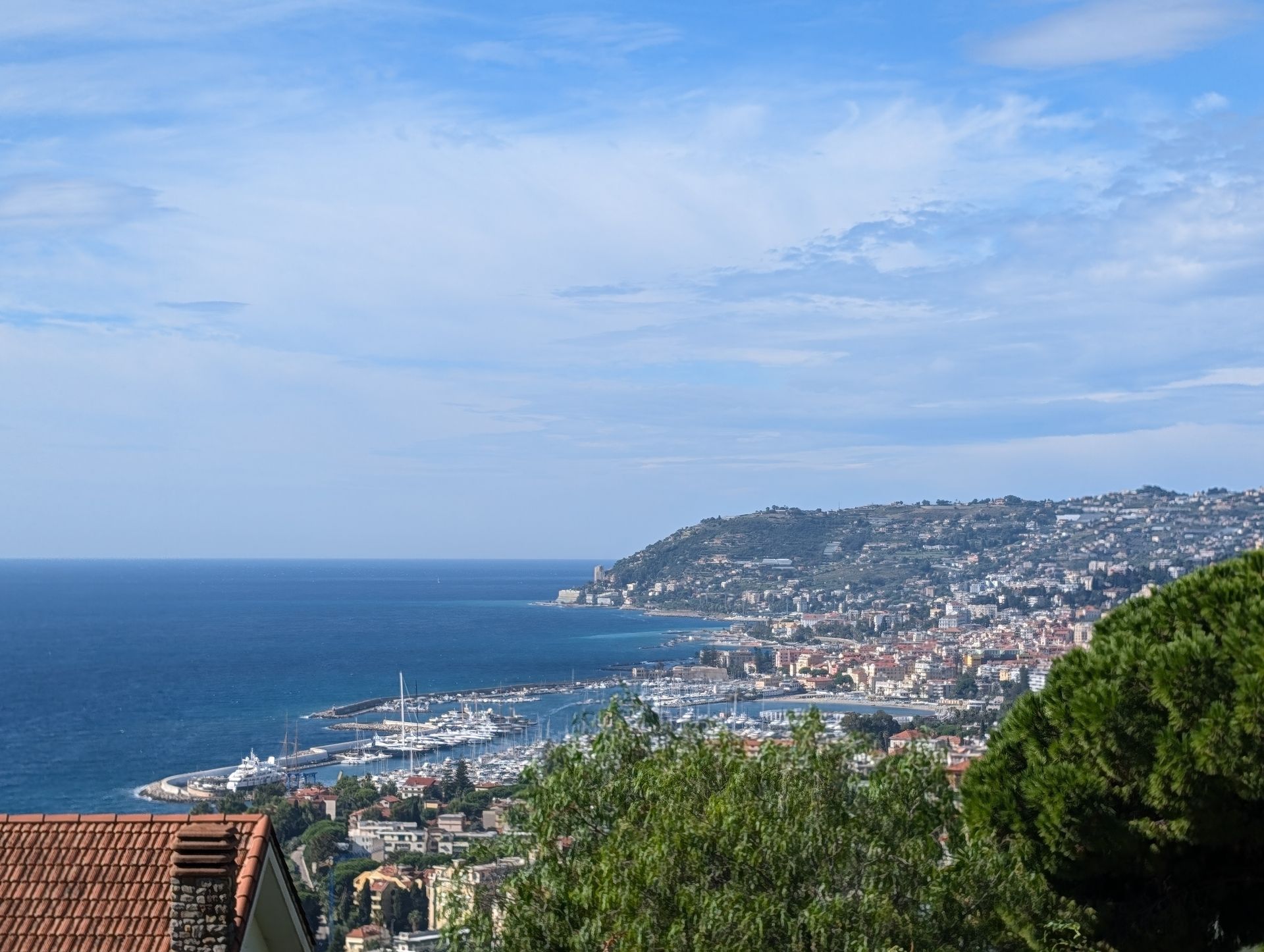 Coastal city overlooking a blue sea under a partly cloudy sky.