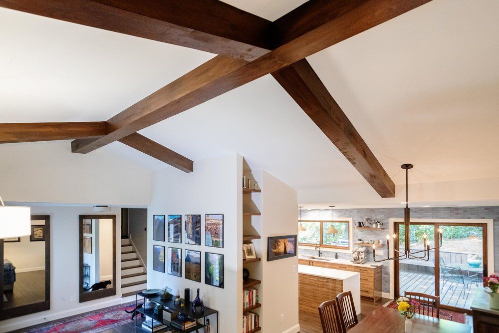 Interior view of a living space with exposed wooden beams on the ceiling, kitchen, and dining area.