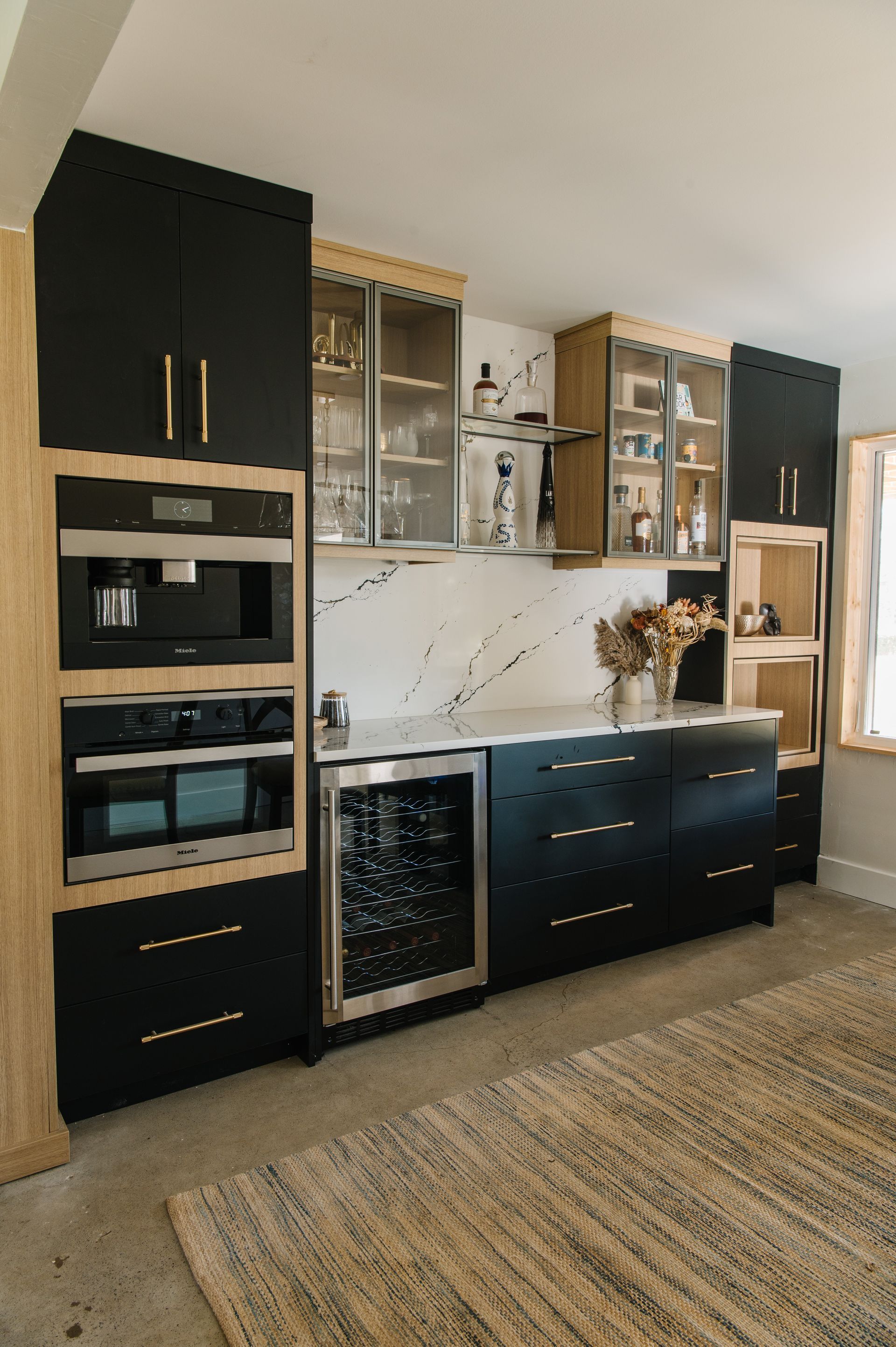 Modern black and wood kitchen with built-in appliances, a wine fridge, and open shelving.