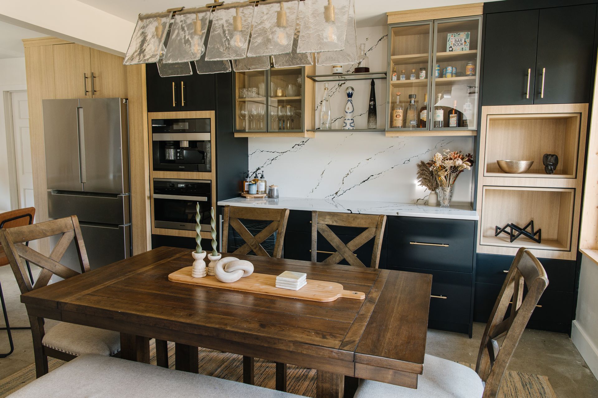 Kitchen with dark and light wood cabinets, stainless steel appliances, and a wooden dining table.