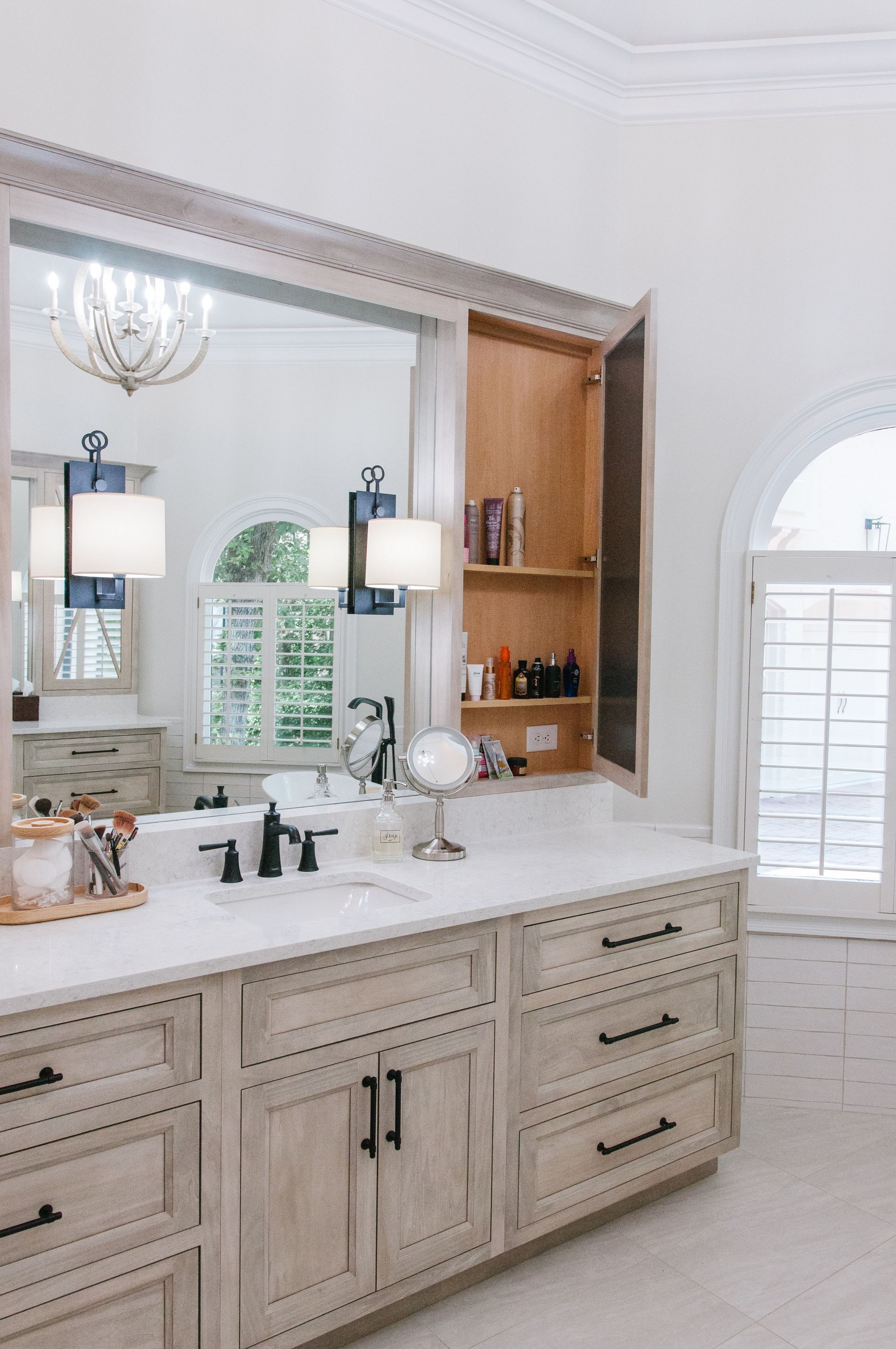 Bathroom vanity with a large mirror, built-in storage, and a marble countertop.