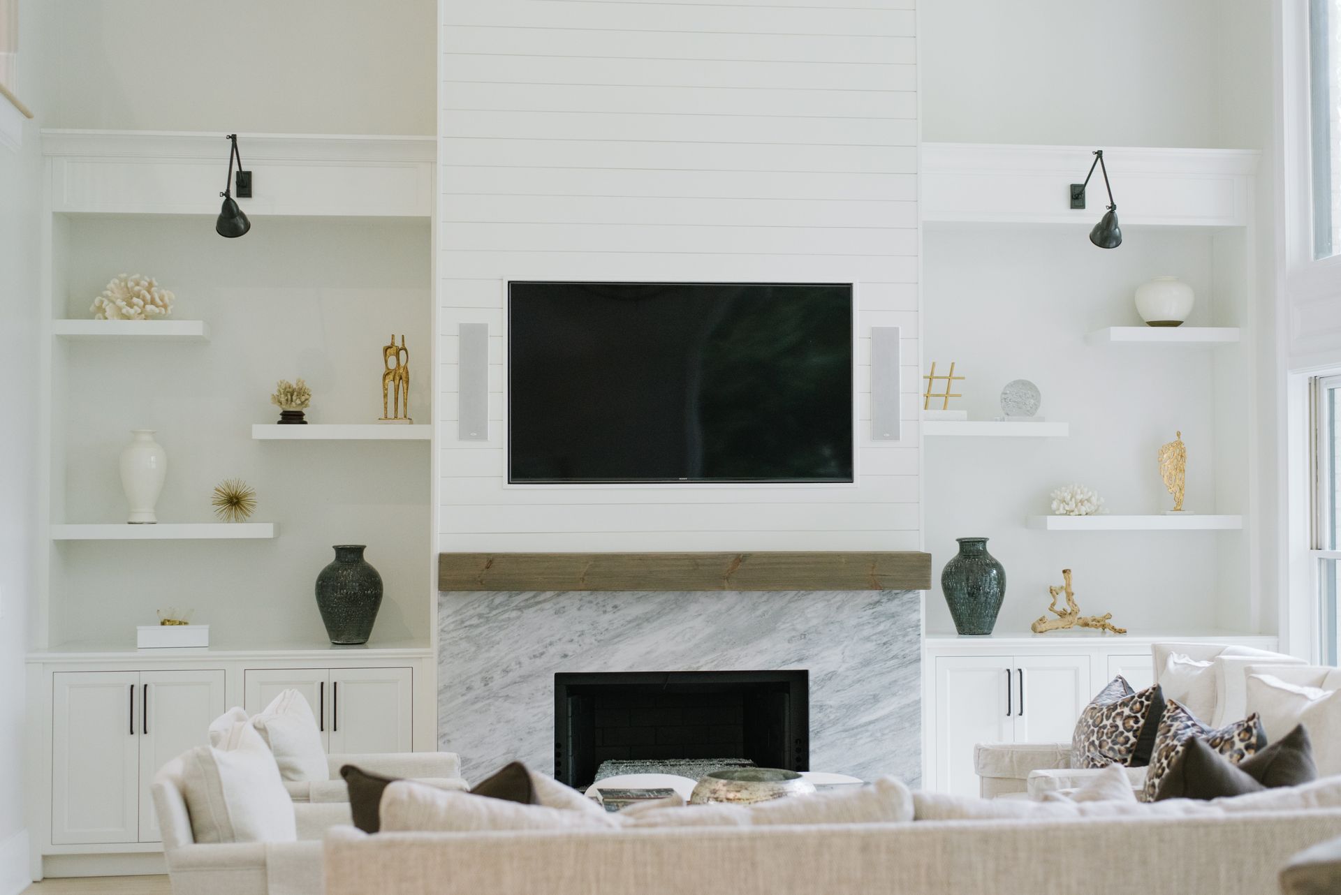 Living room with a white built-in fireplace, shelves, TV, and decorative items.