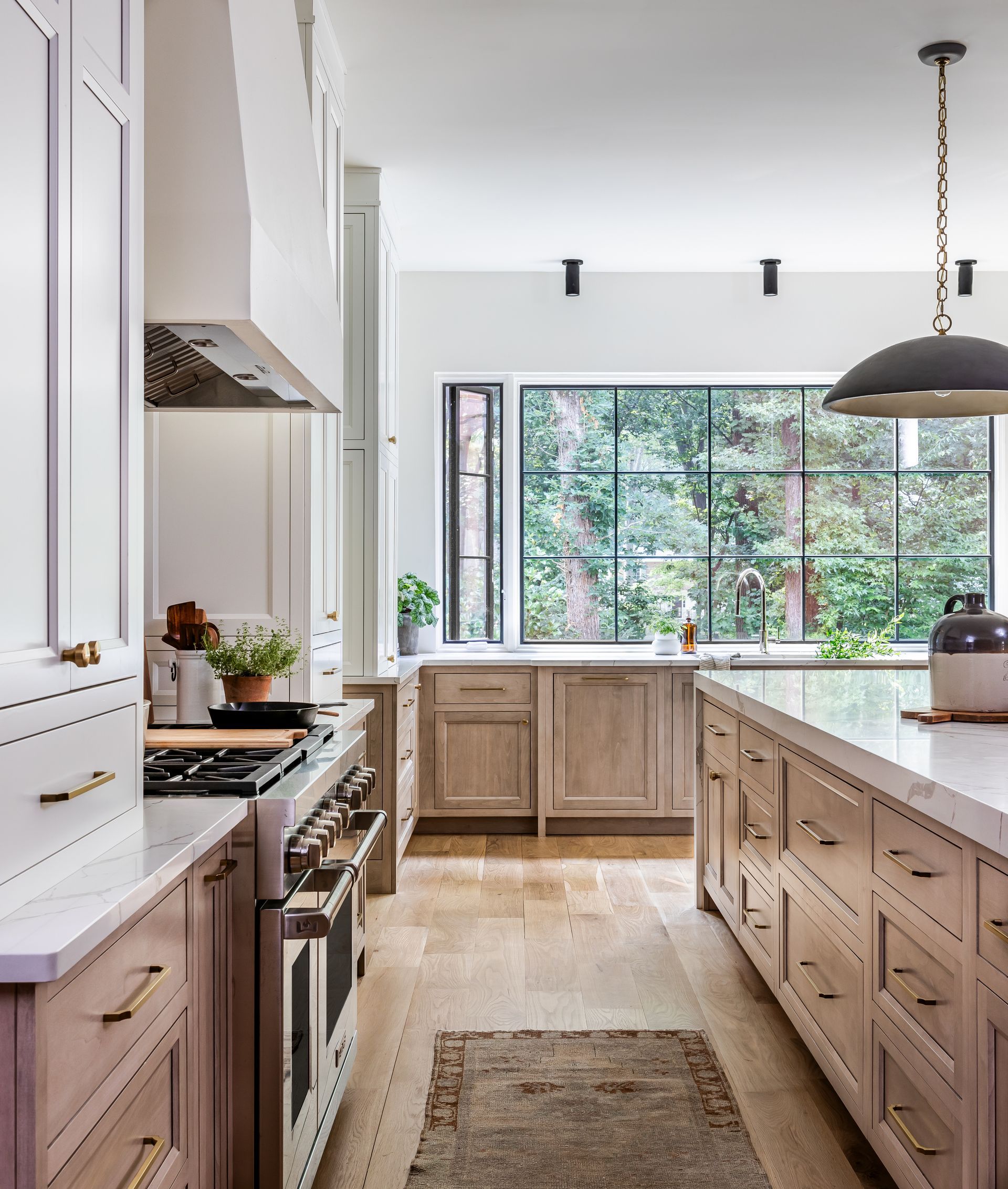 Spacious kitchen with wood cabinets, white countertops, and a large window overlooking trees.