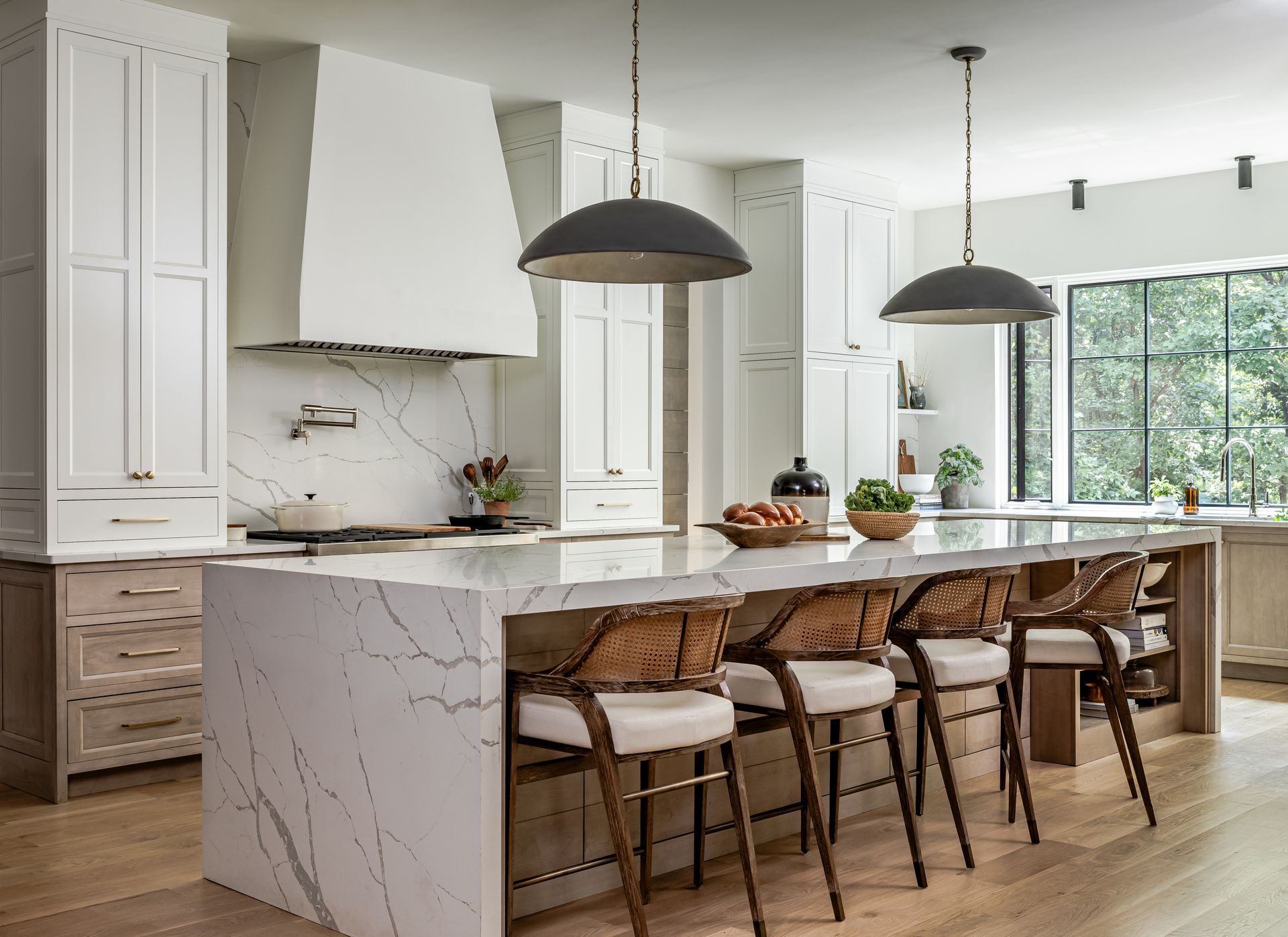 Modern kitchen with white cabinets, marble island, and pendant lights.