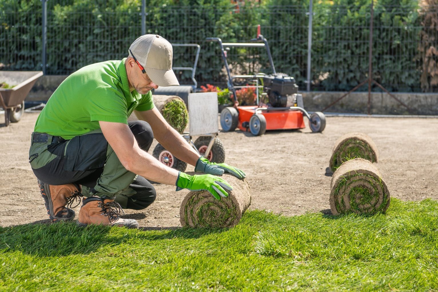 A professional landscaper works on unrolling turf on a commercial property - 1st Impression Turf