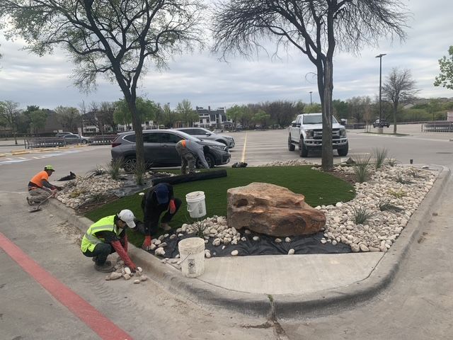 A group of people are working on a lawn in a parking lot.