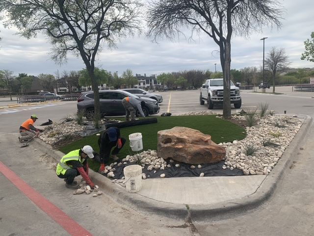 1st Impression staff are decorating a landscape island with stone and rocks.