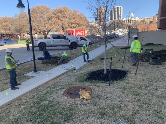 A group of construction workers are working on a sidewalk.