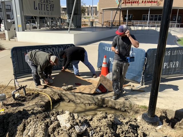 A group of men are working in the dirt in front of a sign that says plaza
