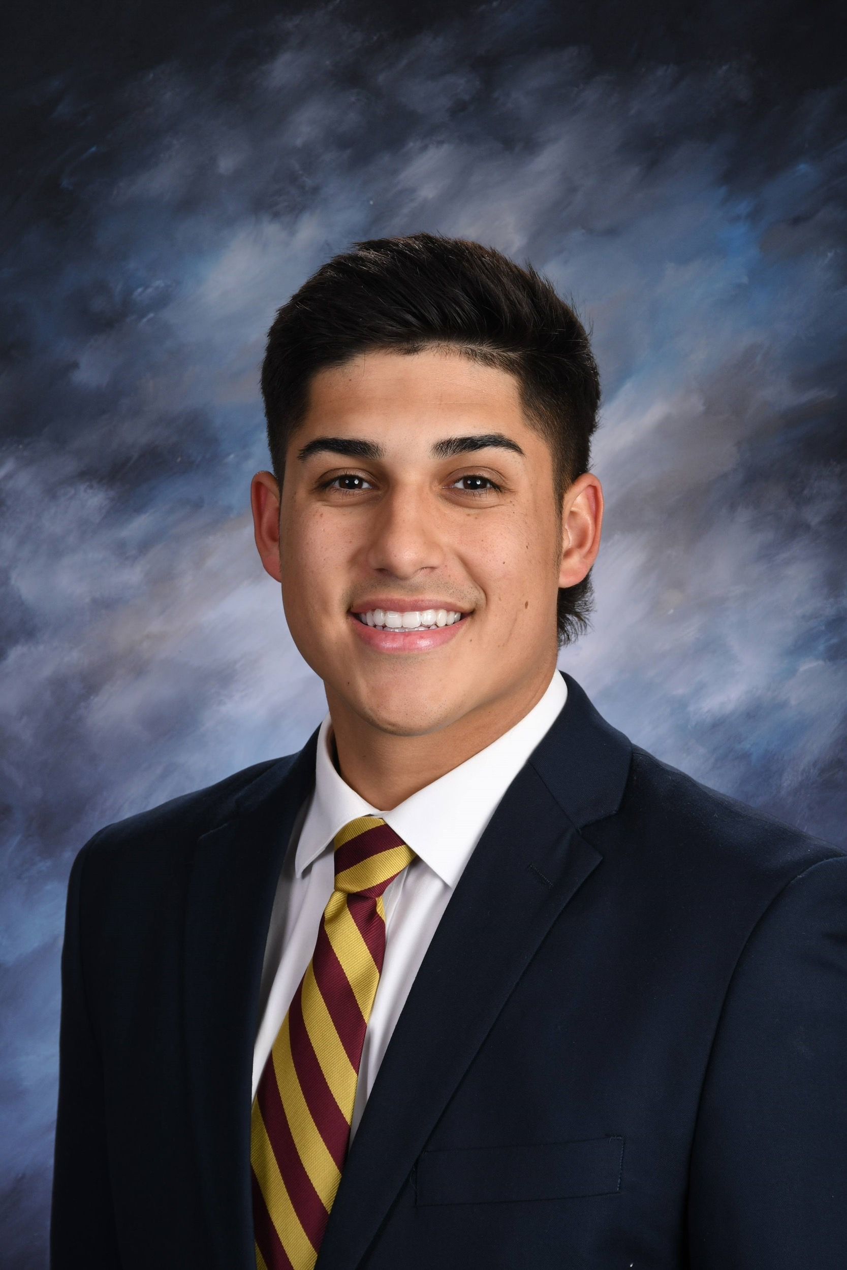 A young man in a suit and tie is smiling for the camera.