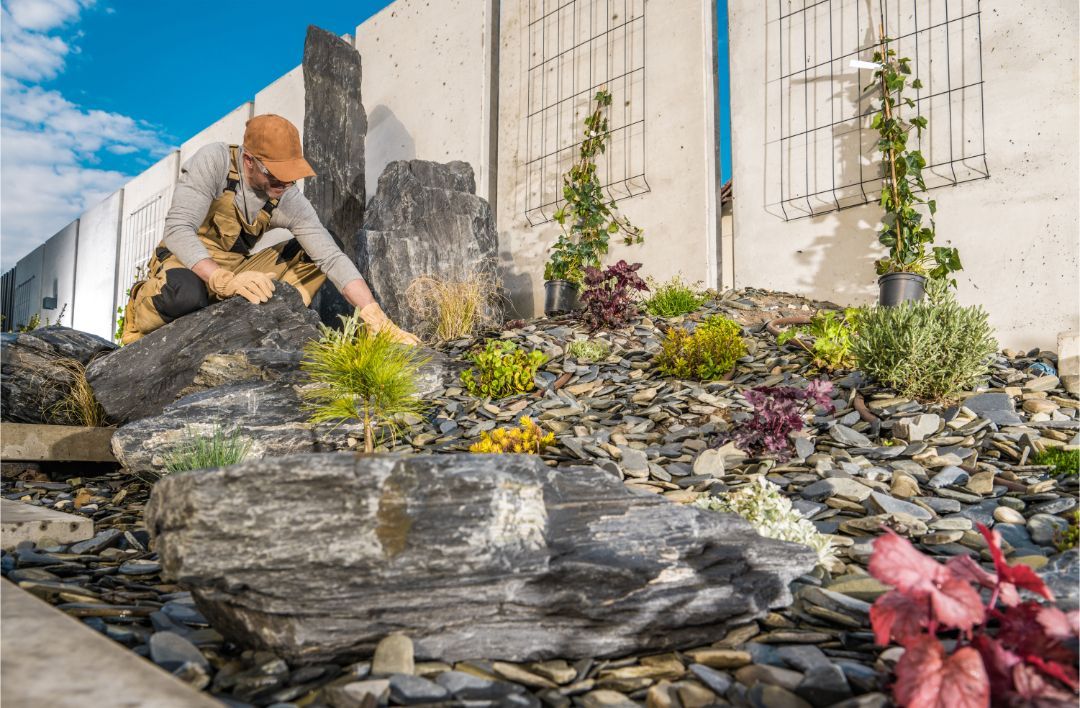 A man is kneeling down in a rock garden.